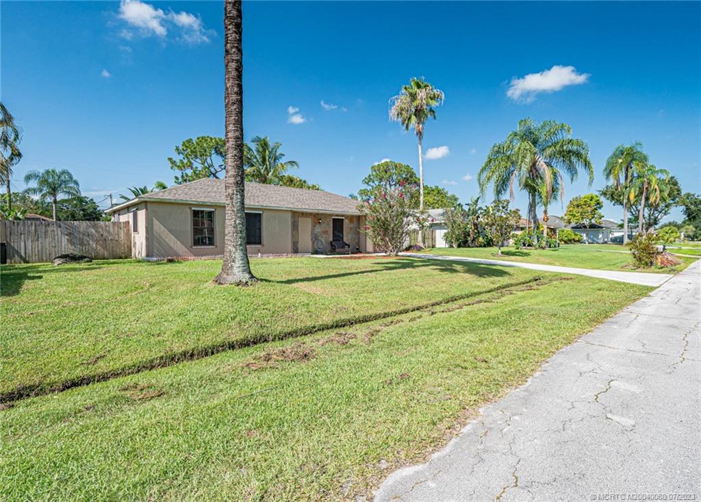 662 Southeast Ron Rico Terrace Port St. Lucie, FL 34983 - Photo 26 of 27 a front view of a house with a yard and palm trees