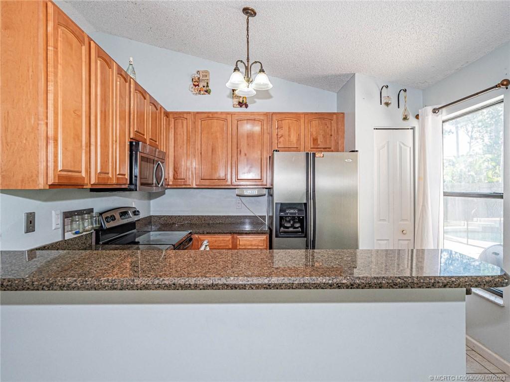 662 Southeast Ron Rico Terrace Port St. Lucie, FL 34983 - Photo 5 of 27 a kitchen with stainless steel appliances granite countertop a sink a refrigerator and a granite counter tops