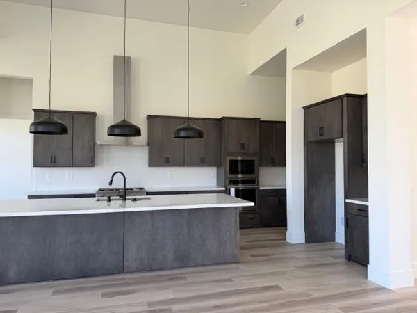 a kitchen with kitchen island stainless steel appliances a sink a refrigerator a stove and wooden floor