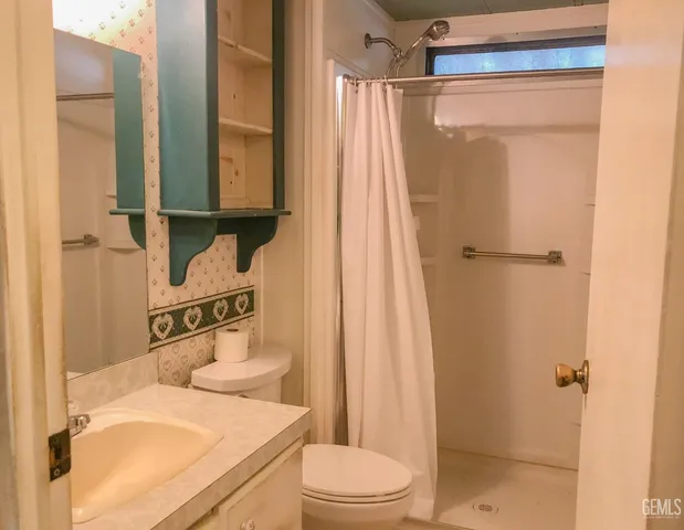 a bathroom with a granite countertop sink a toilet a mirror and a window