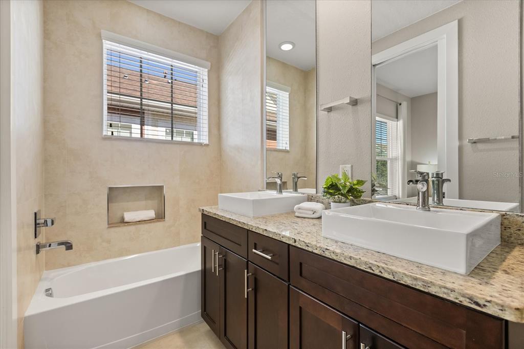 2637 Sunrise Shores Drive Kissimmee, FL 34747 - Photo 27 of 39 a bathroom with a granite countertop tub sink and mirror