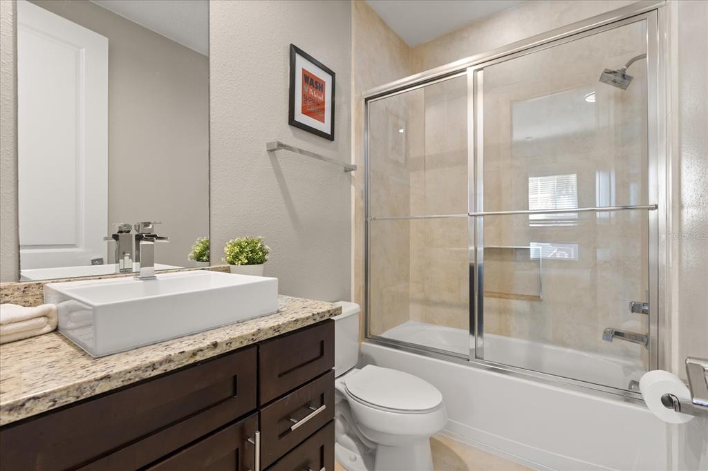 2637 Sunrise Shores Drive Kissimmee, FL 34747 - Photo 28 of 39 a bathroom with a granite countertop sink toilet and shower