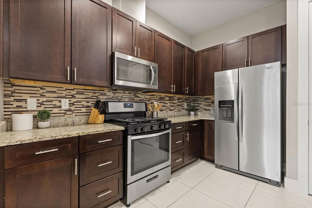 2637 Sunrise Shores Drive Kissimmee, FL 34747 - Photo 6 of 39 a kitchen with stainless steel appliances granite countertop a stove a refrigerator and a sink