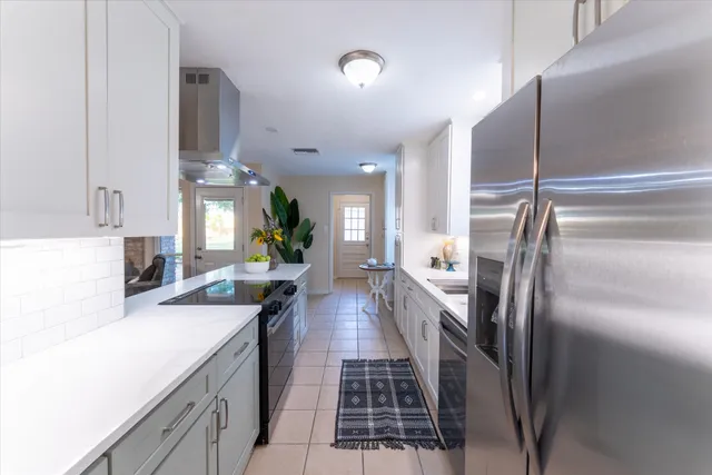 an empty room with wooden floor chandelier fan and windows