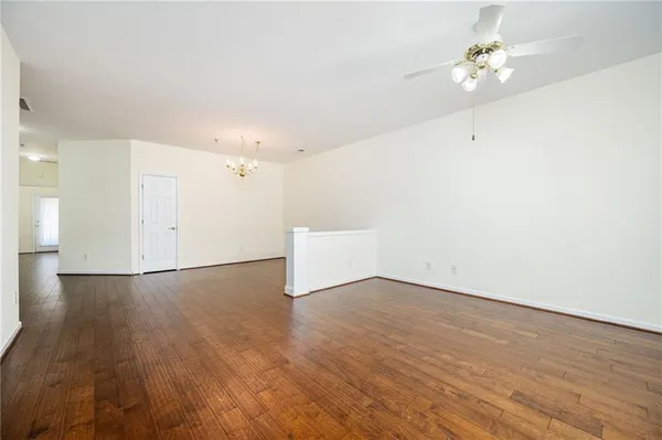 an empty room with wooden floor and ceiling fan