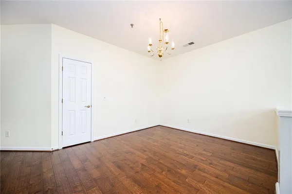 an empty room with wooden floor and chandelier fan