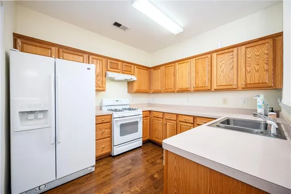 a kitchen with stainless steel appliances granite countertop a refrigerator a sink dishwasher and wooden cabinets with wooden floor
