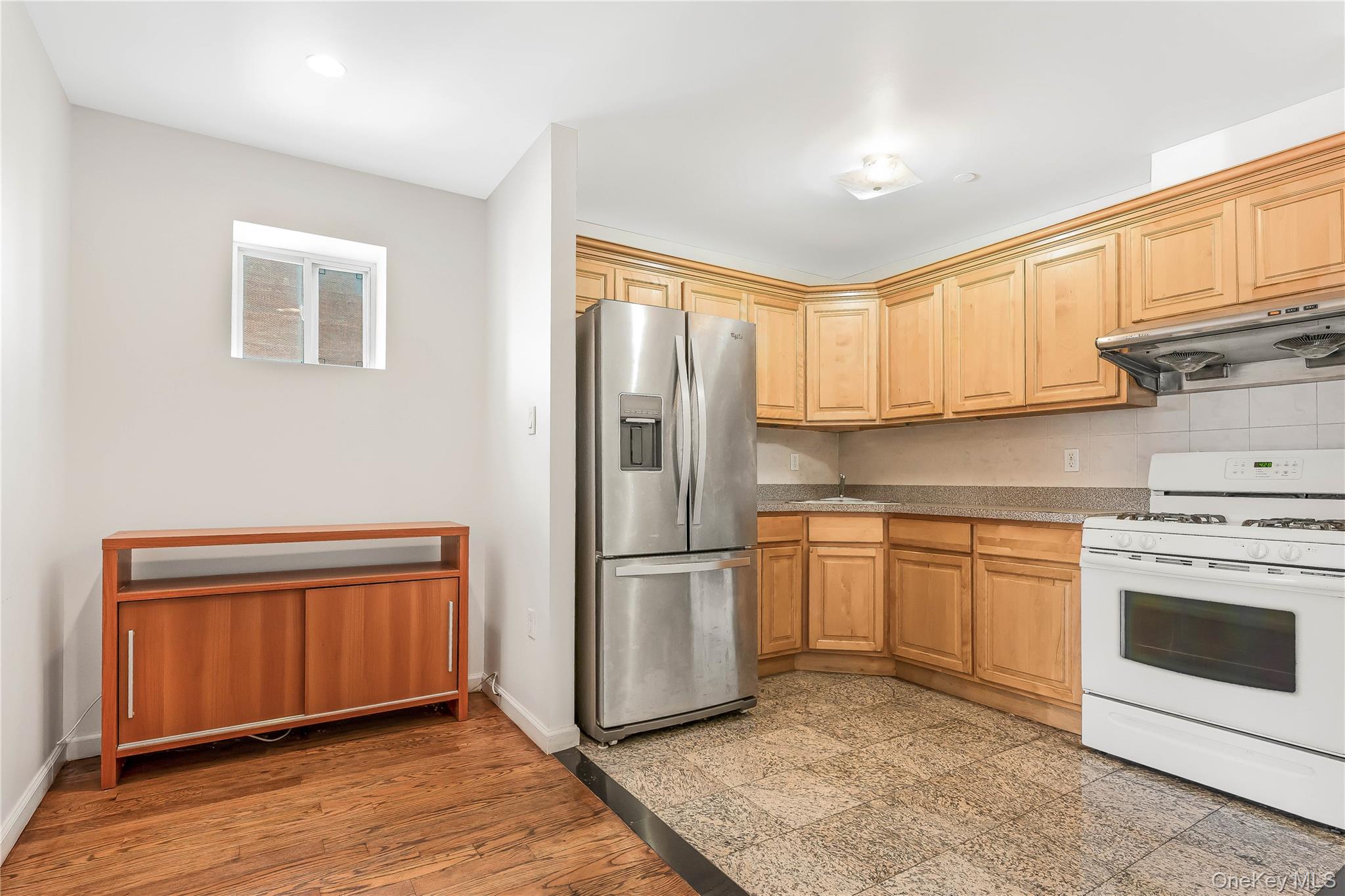 85-23 Broadway, Unit 7C Queens, NY 11373 - Photo 2 of 33 Kitchen with stainless steel fridge, white gas stove, range hood, and decorative backsplash