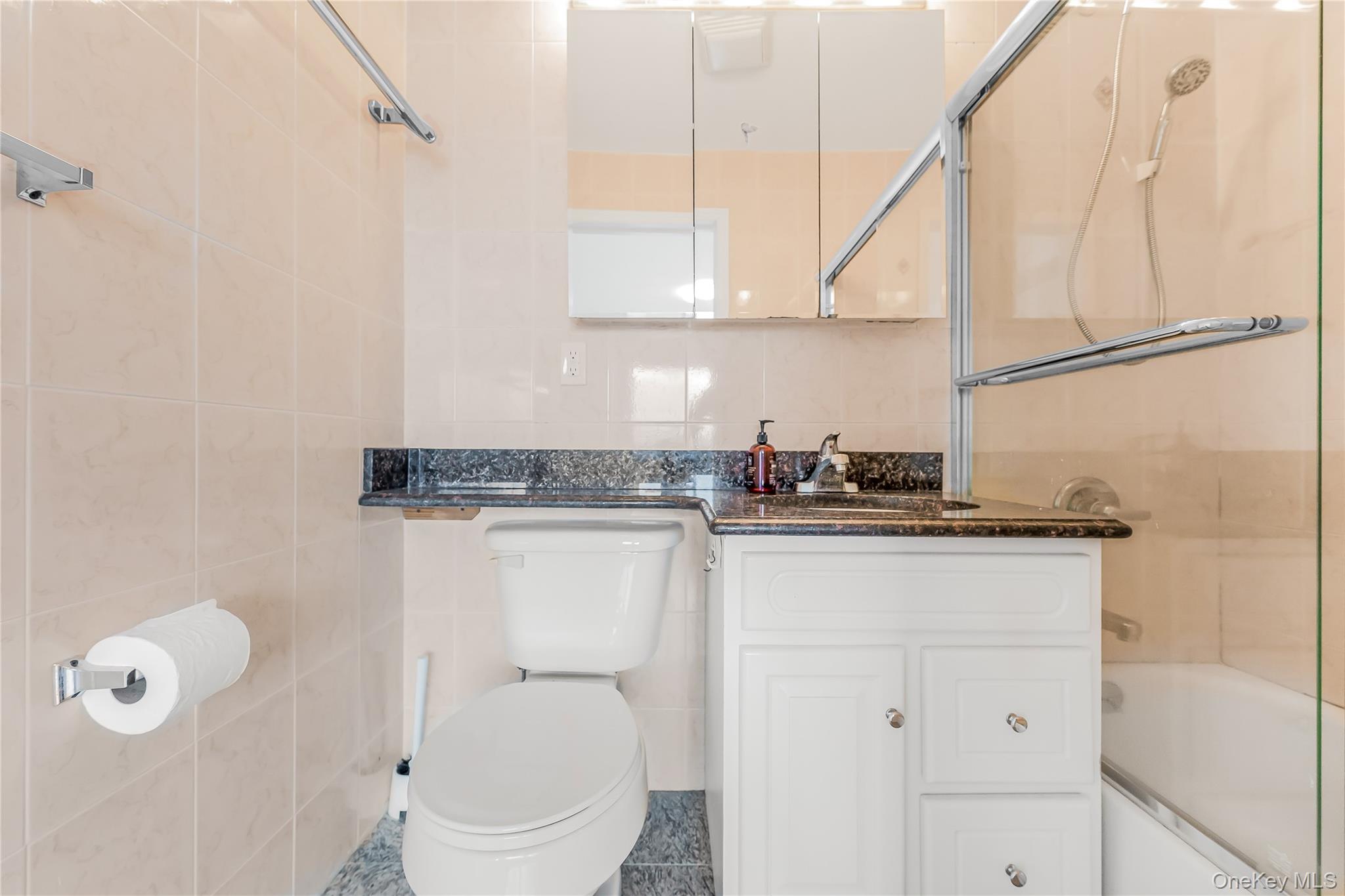 85-23 Broadway, Unit 7C Queens, NY 11373 - Photo 24 of 33 Bathroom with tile walls, combined bath / shower with glass door, and vanity