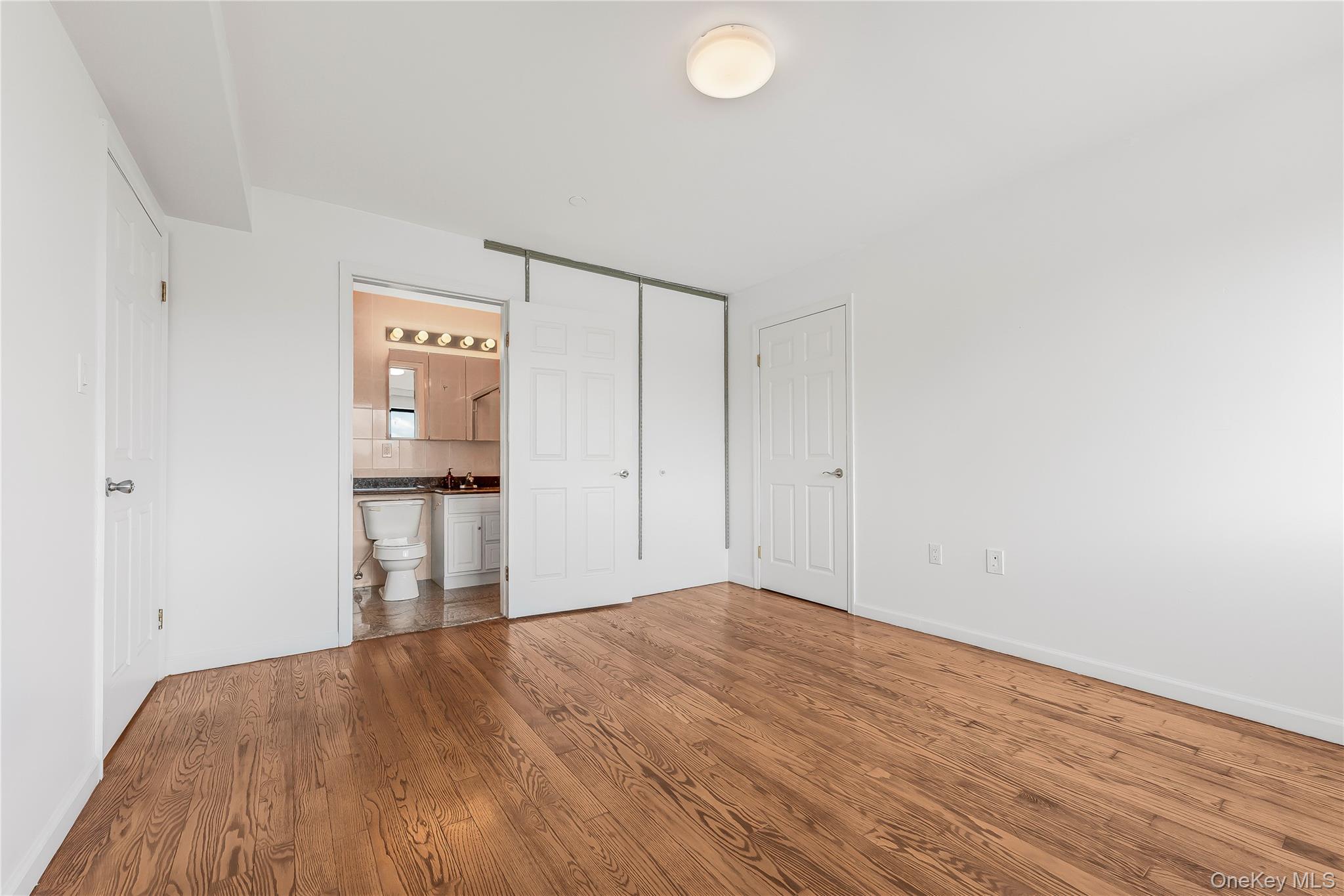 85-23 Broadway, Unit 7C Queens, NY 11373 - Photo 25 of 33 Unfurnished bedroom with wood finished floors, ensuite bath, and a closet