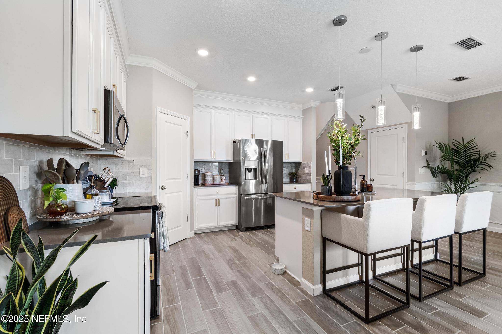 155 Appleton Court St. Augustine, FL 32092 - Photo 9 of 56 a kitchen with stainless steel appliances kitchen island granite countertop a refrigerator a stove a sink dishwasher and white cabinets with wooden floor