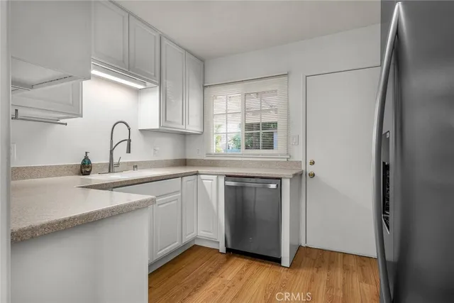 a kitchen with granite countertop a sink cabinets and stainless steel appliances