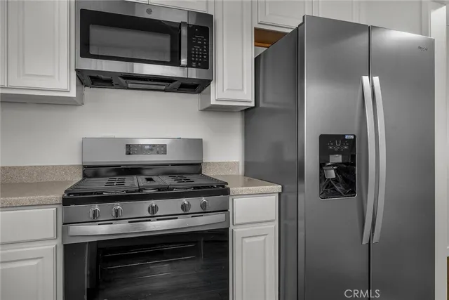 a kitchen with stainless steel appliances granite countertop white cabinets and a stove top oven