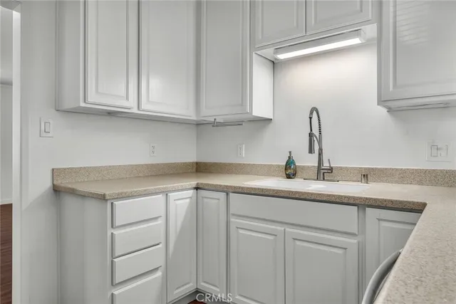 a kitchen with white cabinets and sink
