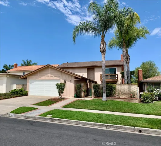 a front view of a house with a garden and palm trees