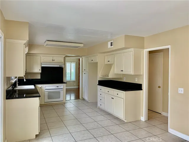 a kitchen with granite countertop a sink a stove and refrigerator