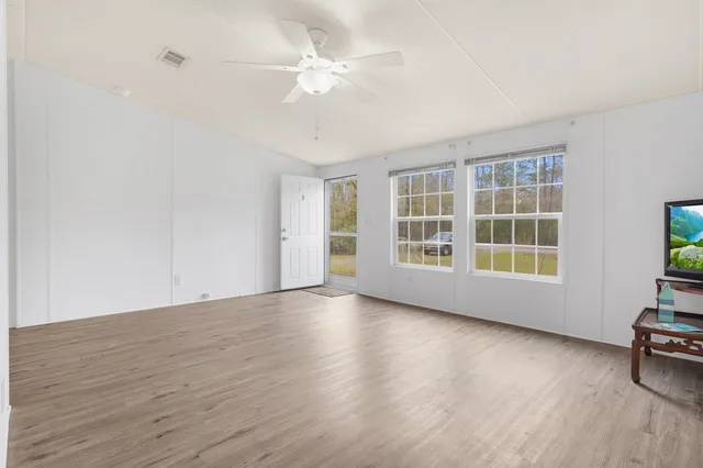 a view of an empty room with a window and wooden floor