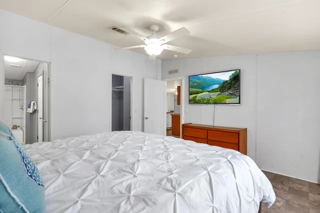 a bedroom with a bed a flat screen tv and a chandelier