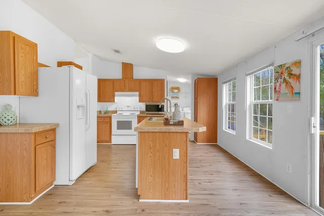 a kitchen with stainless steel appliances granite countertop a refrigerator a stove top oven a sink dishwasher and wooden floor