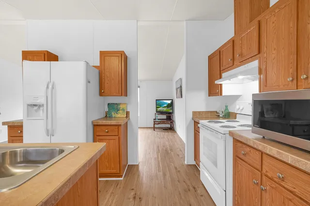 a kitchen with stainless steel appliances granite countertop a sink dishwasher stove and refrigerator with wooden floor