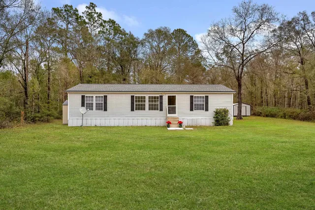 a front view of house with a garden and trees