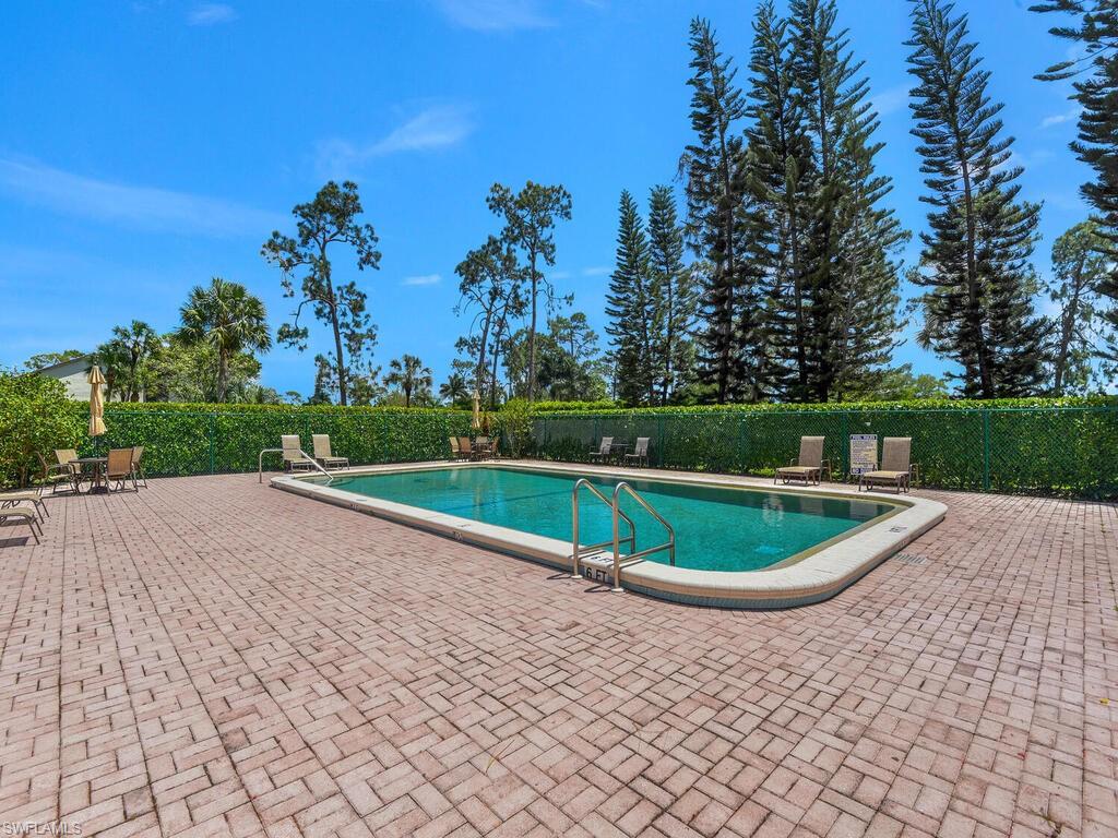 5825 Rattlesnake Hammock Road, Unit 202 Naples, FL 34113 - Photo 26 of 30 a house with a yard and trees in the background