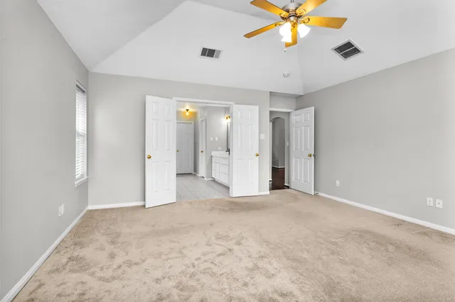 a view of an empty room with window and a chandelier fan