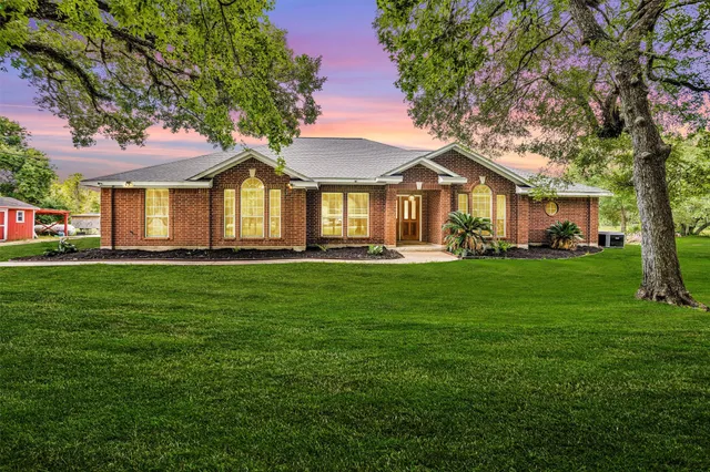 a front view of a house with a garden and trees