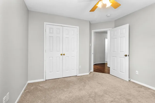 an empty room with windows and chandelier fan