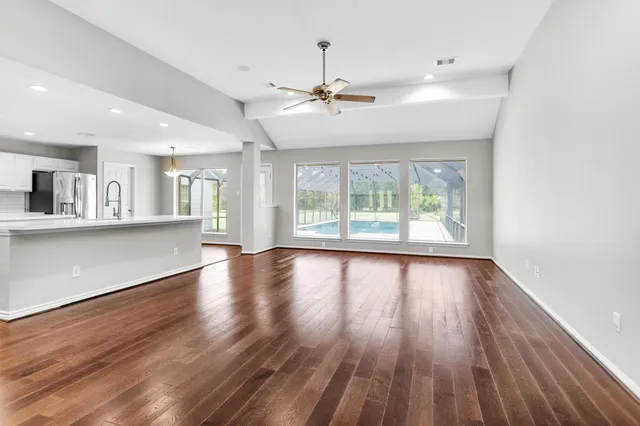 an empty room with wooden floor and windows