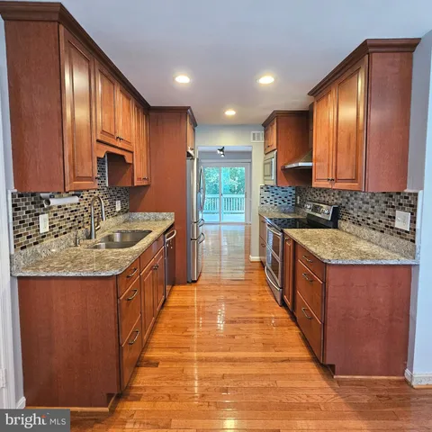 a large kitchen with kitchen island granite countertop a sink and a stove top oven