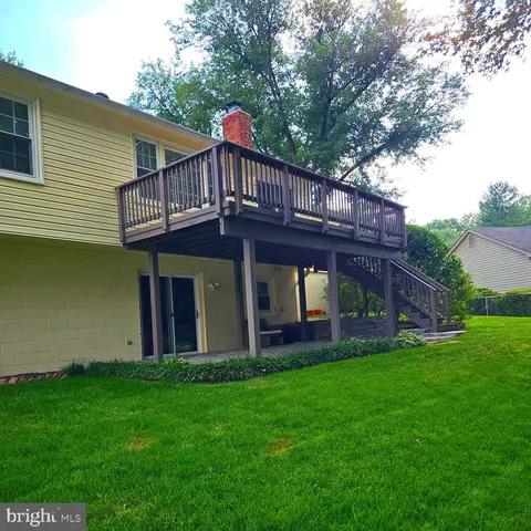 a backyard of a house with wooden fence and large trees