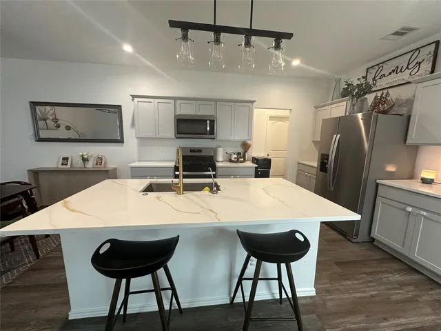 a kitchen with stainless steel appliances a table chairs and refrigerator