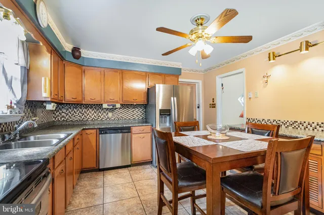 a kitchen with stainless steel appliances granite countertop a sink a stove a dining table and chairs