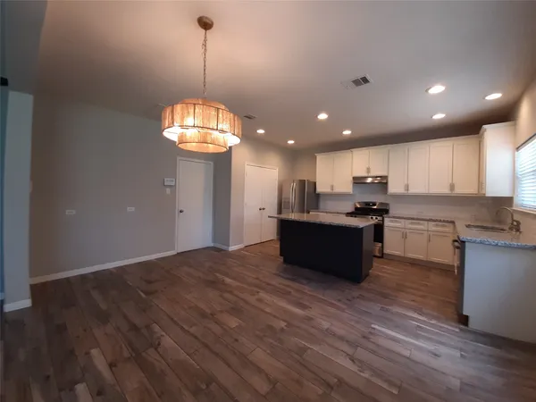 a kitchen with kitchen island granite countertop wooden floors stainless steel appliances and window