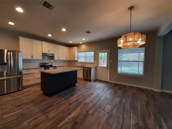 a large kitchen with stainless steel appliances granite countertop a stove a refrigerator a sink dishwasher and a oven with wooden floor