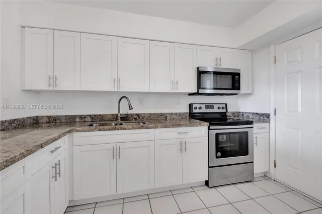 a kitchen with white cabinets stainless steel appliances and sink