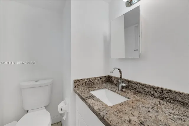 a bathroom with a granite countertop sink and a toilet