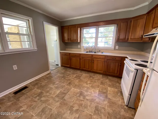 a kitchen with granite countertop a sink window and cabinets