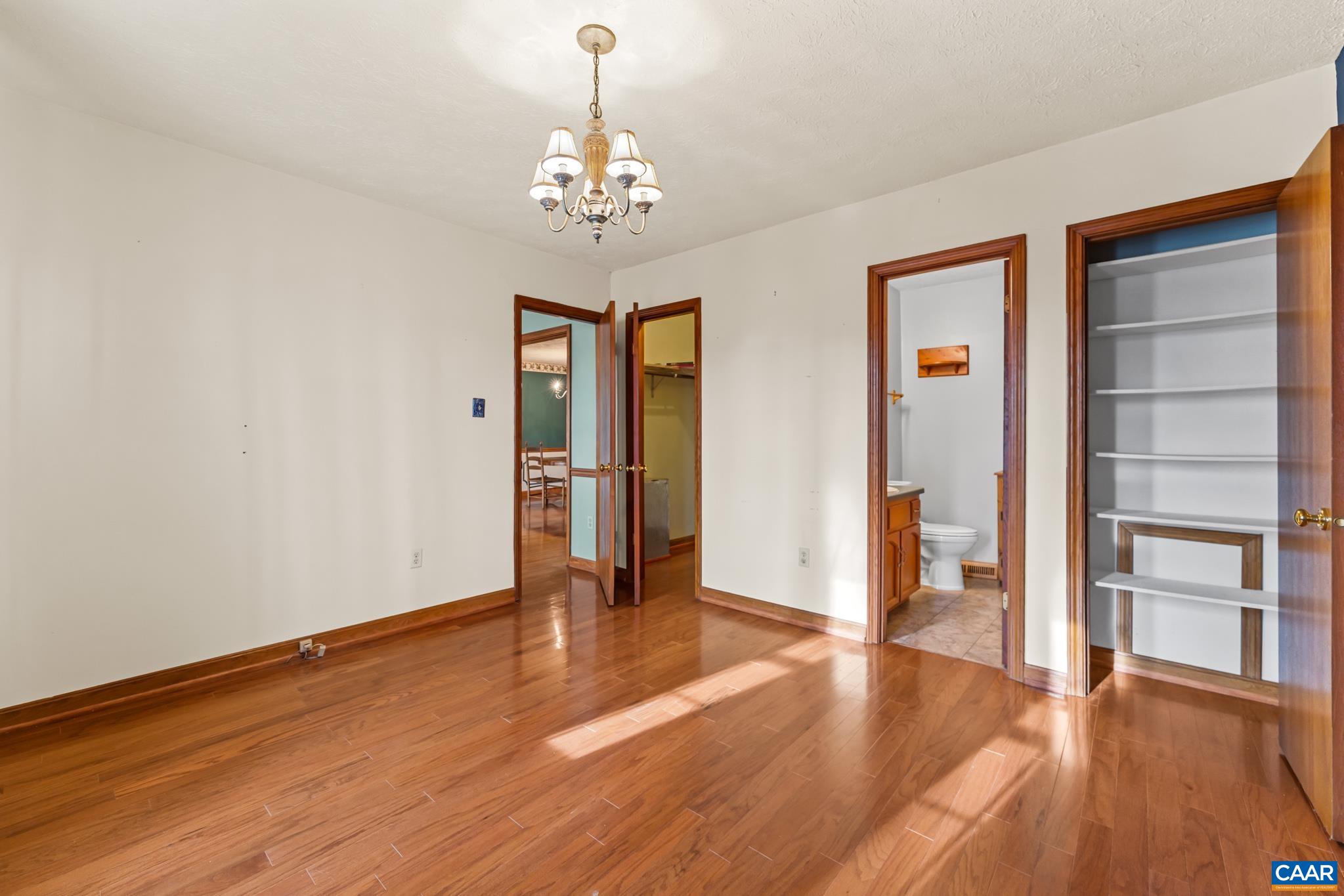 987 Matthew Mill Road Ruckersville, VA 22968 - Photo 16 of 63 Flexible living space with beautiful wood floors, classic wood trim, and a timeless chandelier. This room offers seamless access to a full bath, ample built-in shelving in the walk-in closet, and other areas of the home through multiple doorways.