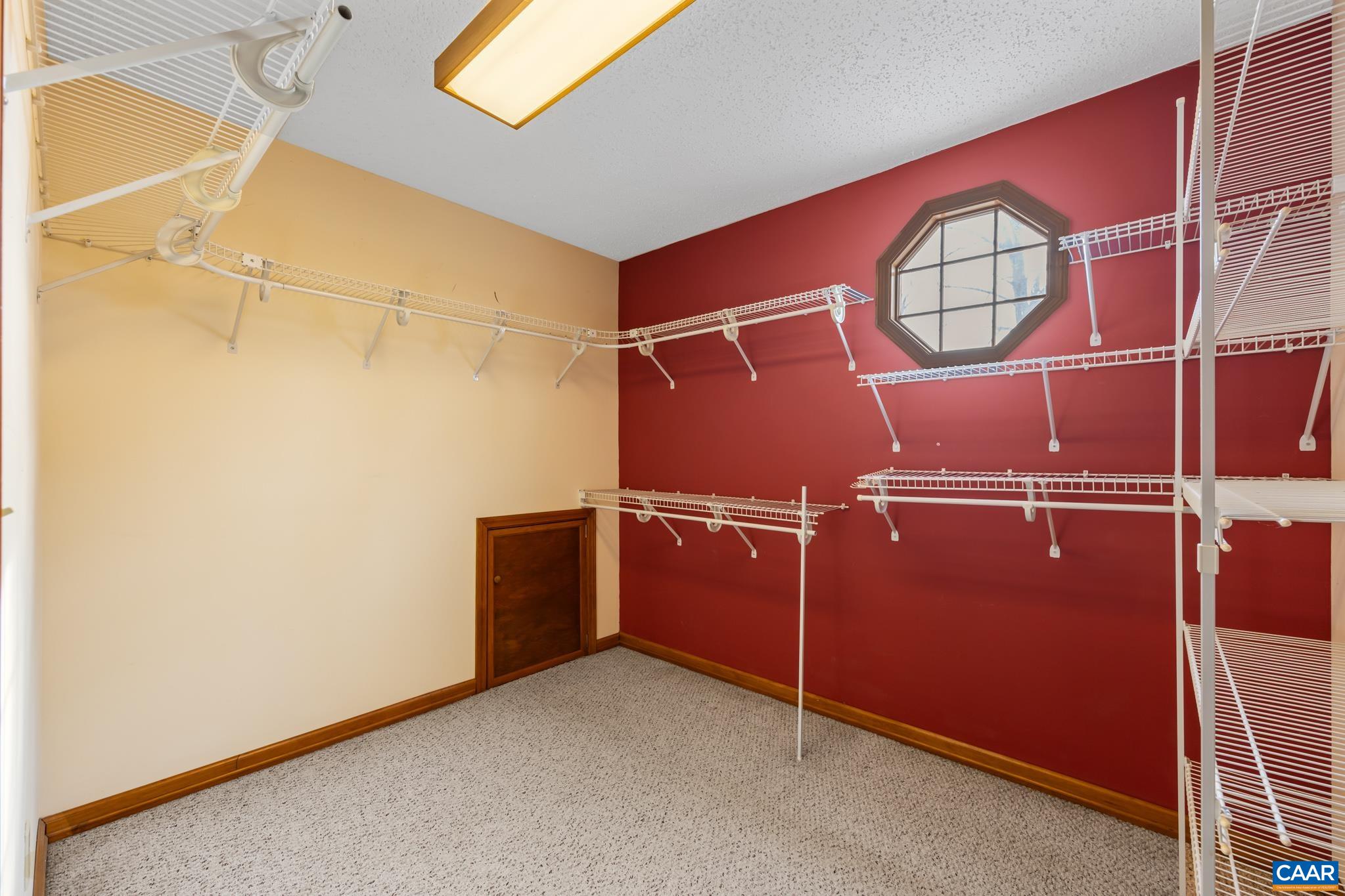 987 Matthew Mill Road Ruckersville, VA 22968 - Photo 37 of 63 A massive walk-in closet awaits, featuring built-in wire shelving on all sides, two-tone walls, and an architectural octagonal window. Enjoy plush carpeting and a versatile and bright space for organization.