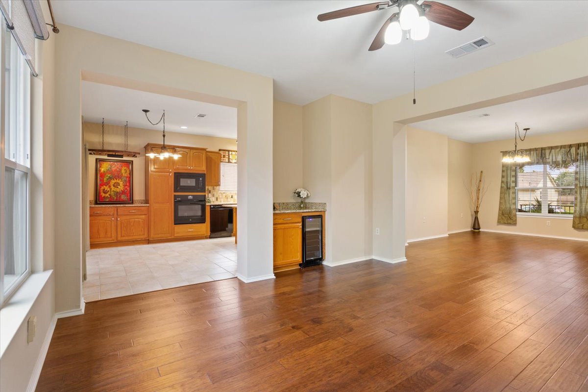 246 Red Poppy Trail Georgetown, TX 78633 - Photo 12 of 32 a view of an empty room with wooden floor and a kitchen