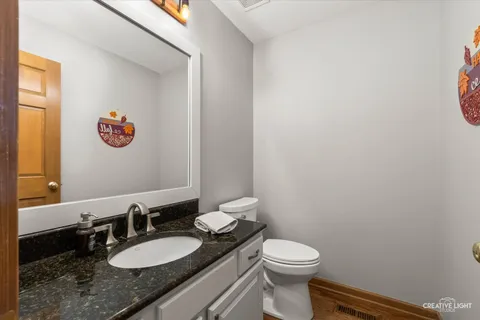 a bathroom with a granite countertop sink mirror vanity and toilet