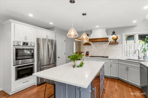 a kitchen with stainless steel appliances a sink a stove a refrigerator cabinets and wooden floor