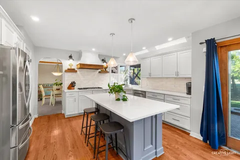 a kitchen with kitchen island a stove a table and chairs in it