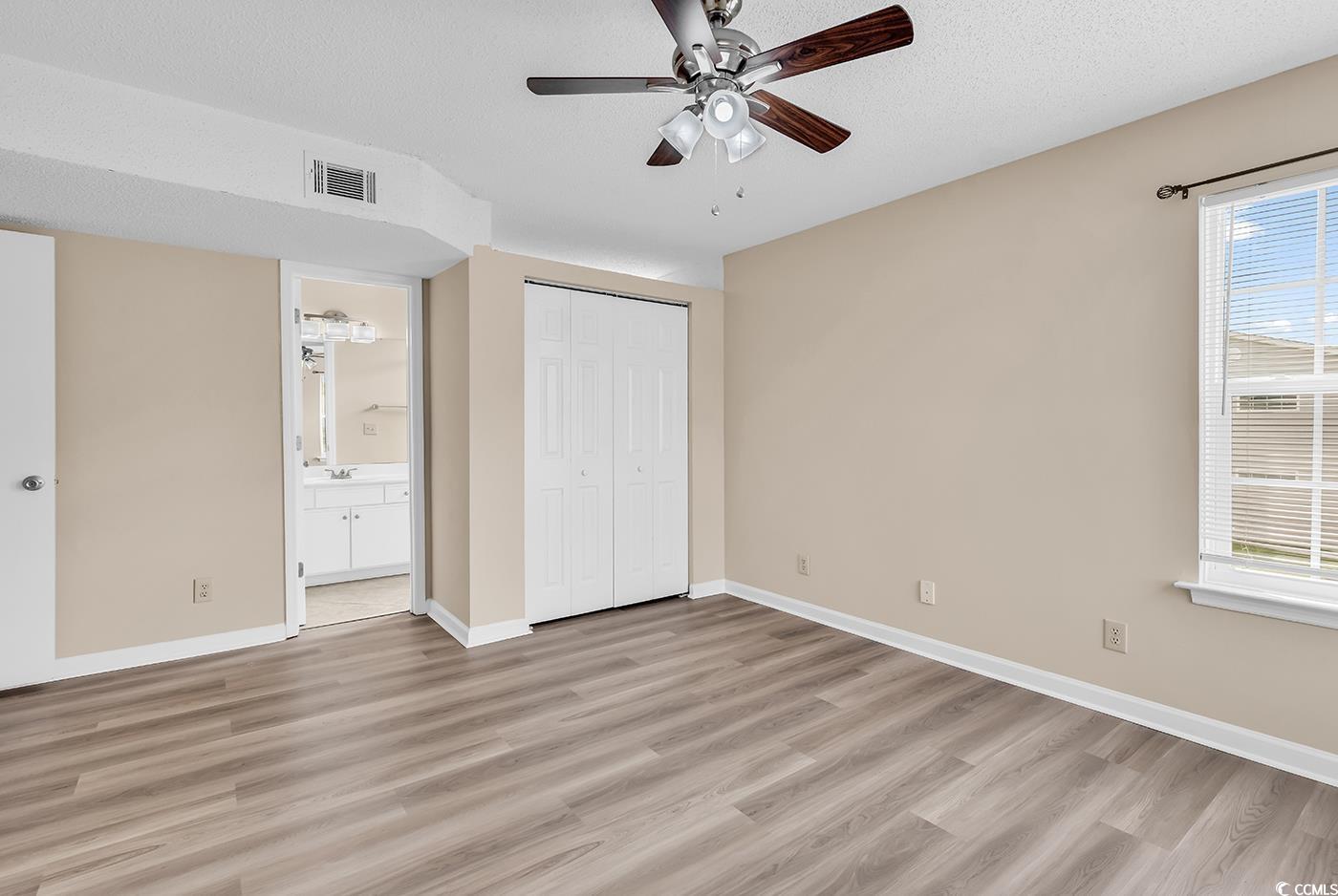 8796 Chandler Drive, Unit F Surfside Beach, SC 29575 - Photo 17 of 21 Unfurnished bedroom with light wood-type flooring, a closet, ceiling fan, a textured ceiling, and ensuite bathroom