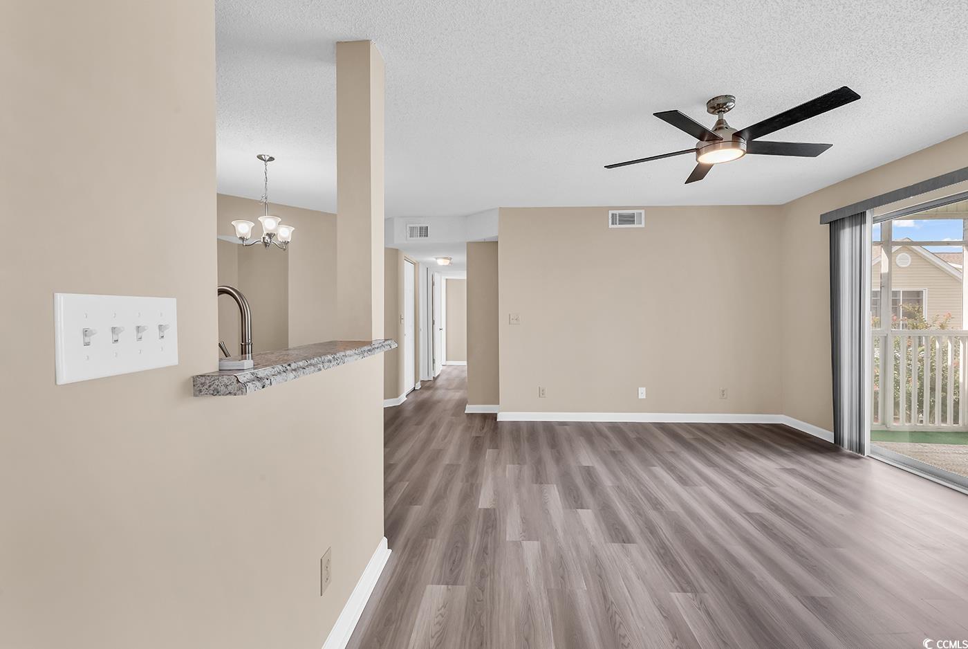 8796 Chandler Drive, Unit F Surfside Beach, SC 29575 - Photo 3 of 21 Unfurnished living room featuring a textured ceiling, light wood-style flooring, a chandelier, and a ceiling fan