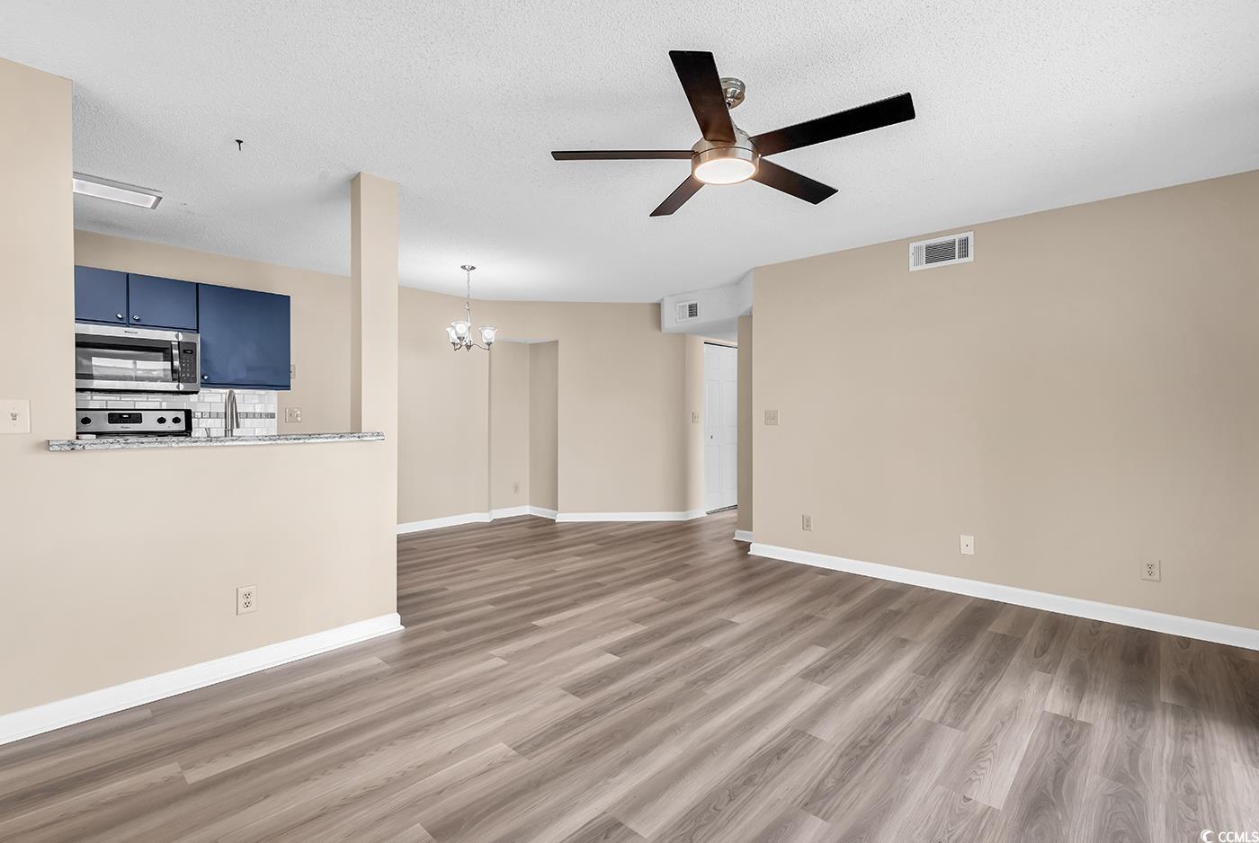 8796 Chandler Drive, Unit F Surfside Beach, SC 29575 - Photo 5 of 21 Unfurnished living room featuring a chandelier, light wood-type flooring, a textured ceiling, and ceiling fan