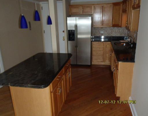 720 West Gordon Terrace, Unit 15L Chicago, IL 60613 - Photo 3 of 12 a kitchen with granite countertop a refrigerator and wooden floor