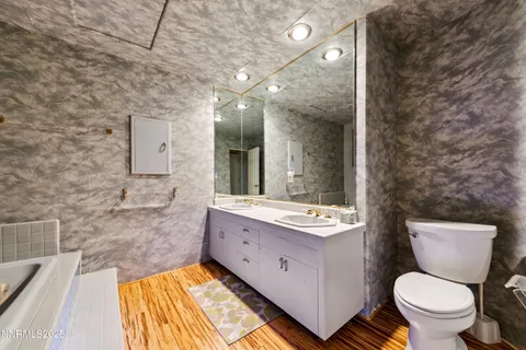 a kitchen with stainless steel appliances kitchen island granite countertop a refrigerator a stove top oven a dining table and chairs with wooden floor